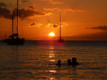 Silhouette sailboat in sea against sky during sunset
