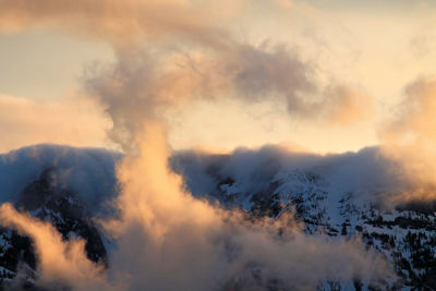 Scenic view of clouds covering mountains against sky during sunset