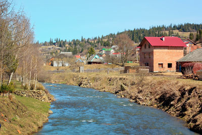 River amidst houses and buildings against clear sky