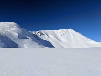 Scenic view of snowcapped mountains against clear blue sky