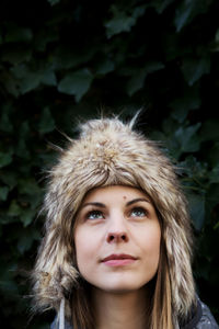 Close-up of young woman wearing warm clothes against plants