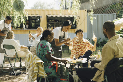 Male and female colleagues serving food to customers at park