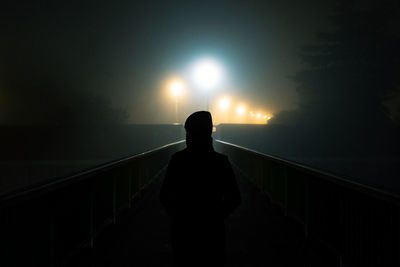 Woman on a bridge in the fog by night