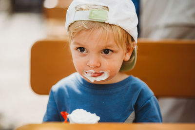 Young white child eating ice cream with dirty mouth and cap