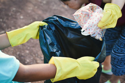 Cropped hands wearing gloves holding garbage bag at park