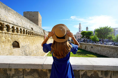 Back view of traveler girl enjoying view of the city of bari from the swabian castle. apulia, italy.