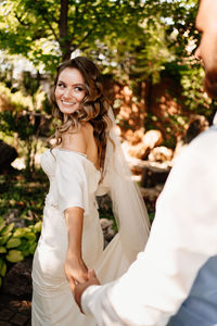 Groom holding brides hand outdoors