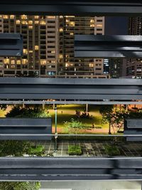 Illuminated road by buildings in city