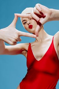 Midsection of woman holding heart shape against blue background