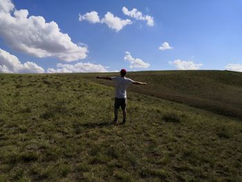 Rear view of man standing on field against sky