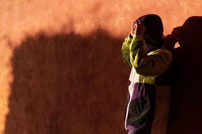 Side view of man standing by wall outdoors