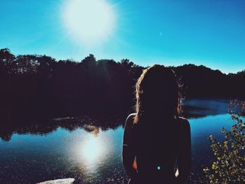 Woman standing in front of lake during sunny day