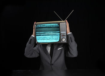 Midsection of person holding smart phone against black background