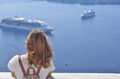 Rear view of young woman standing against sea