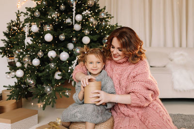 Portrait of smiling girl playing with christmas tree at home