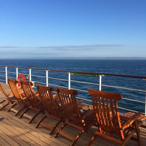 Chairs and table by sea against clear blue sky