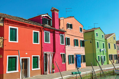 Colorful buildings and boats in front of a canal in burano, a little town full of canals in italy.