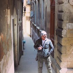 Young man standing in alley during sunny day