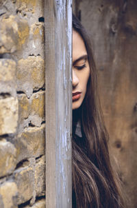 Young woman hiding behind wall