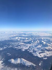 Aerial view of snowcapped landscape against blue sky