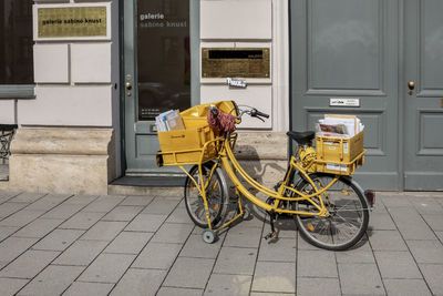 Bicycle parked on footpath against building