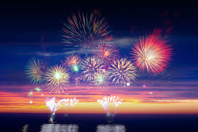 Firework display over sea against sky at night