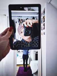 Reflection of woman in hand mirror while photographing through camera