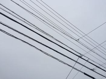 Low angle view of power lines against clear sky