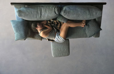 Directly above view of woman sleeping on sofa in living room at home