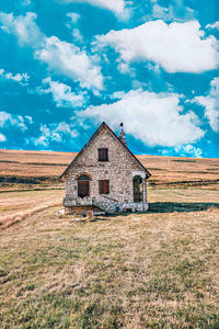 Old house on field against sky