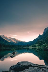 Scenic view of lake and mountains against sky during sunset