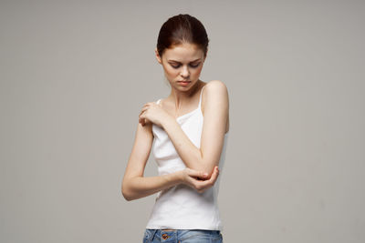 Young woman standing against gray background