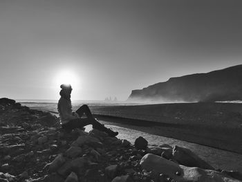 Man on rock at beach against sky