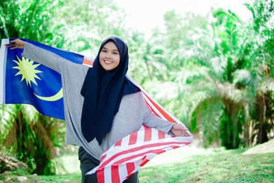 Muslim woman happy holding a malaysian flag. malaysia independence day.