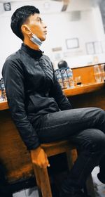 Side view of young man sitting on chair