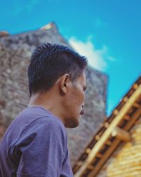 Portrait of man standing against blue sky