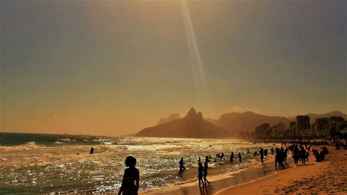 People on beach against sky during sunset