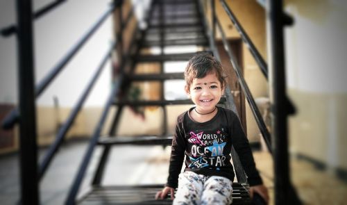 Portrait of smiling boy standing on staircase in playground