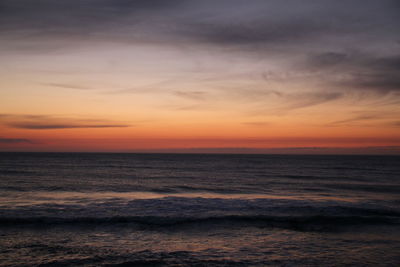 Scenic view of sea against cloudy sky at sunset