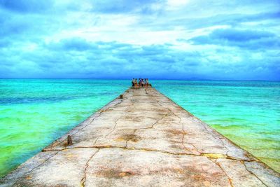 Pier on sea against cloudy sky