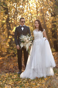 Low section of bride standing in forest