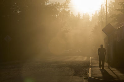 Rear view of man walking on street in city in a dust cloud