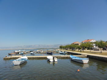 Boats moored in lake against clear blue sky