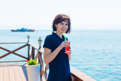 Brunette with a glass of juice in a cafe on the beach.
