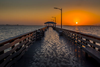 Pier over sea against sky during sunset