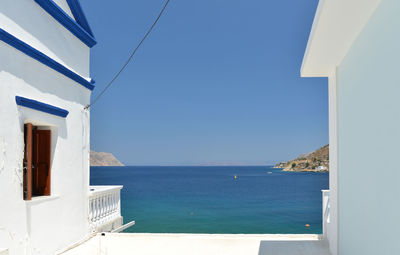 Building by sea against clear blue sky