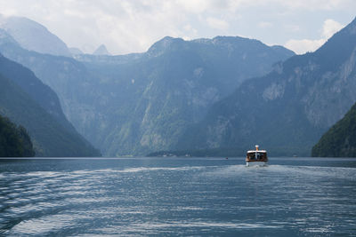 Sailboat sailing in sea against mountain range