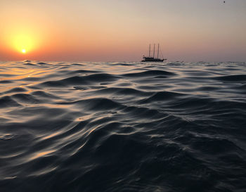 Sailboat sailing in sea against sky during sunset