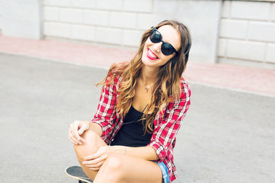 Young woman wearing sunglasses sitting outdoors
