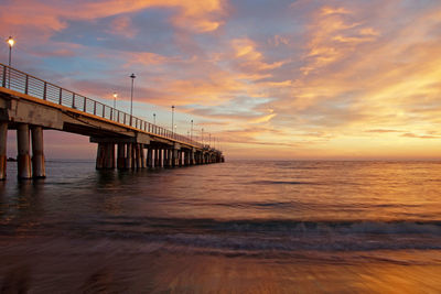 Pier over sea against sky during sunset